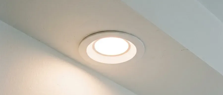 A newly installed recessed LED light glowing in a finished ceiling